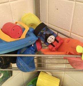 Dirty bath toys on a wire shelf in bathtub