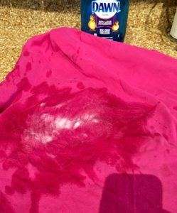 Pink Shirt with soap on it and a bottle of blue Dawn dish soap on a granite counter