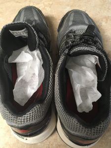Running shoes with coffee filters inside sitting on a counter