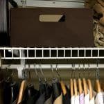 Brown fabric basket on wire shelf in closet with hangers hanging below