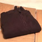 Neatly folded brown sweater on top of a handmade cardboard clothes folder