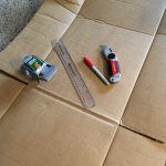 Clothes folder supplies - cardboard, clear plastic ruler, red marker, utility knife, and clear packing tape