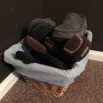 Wicker basket with blue lining full of slippers on a carpet floor